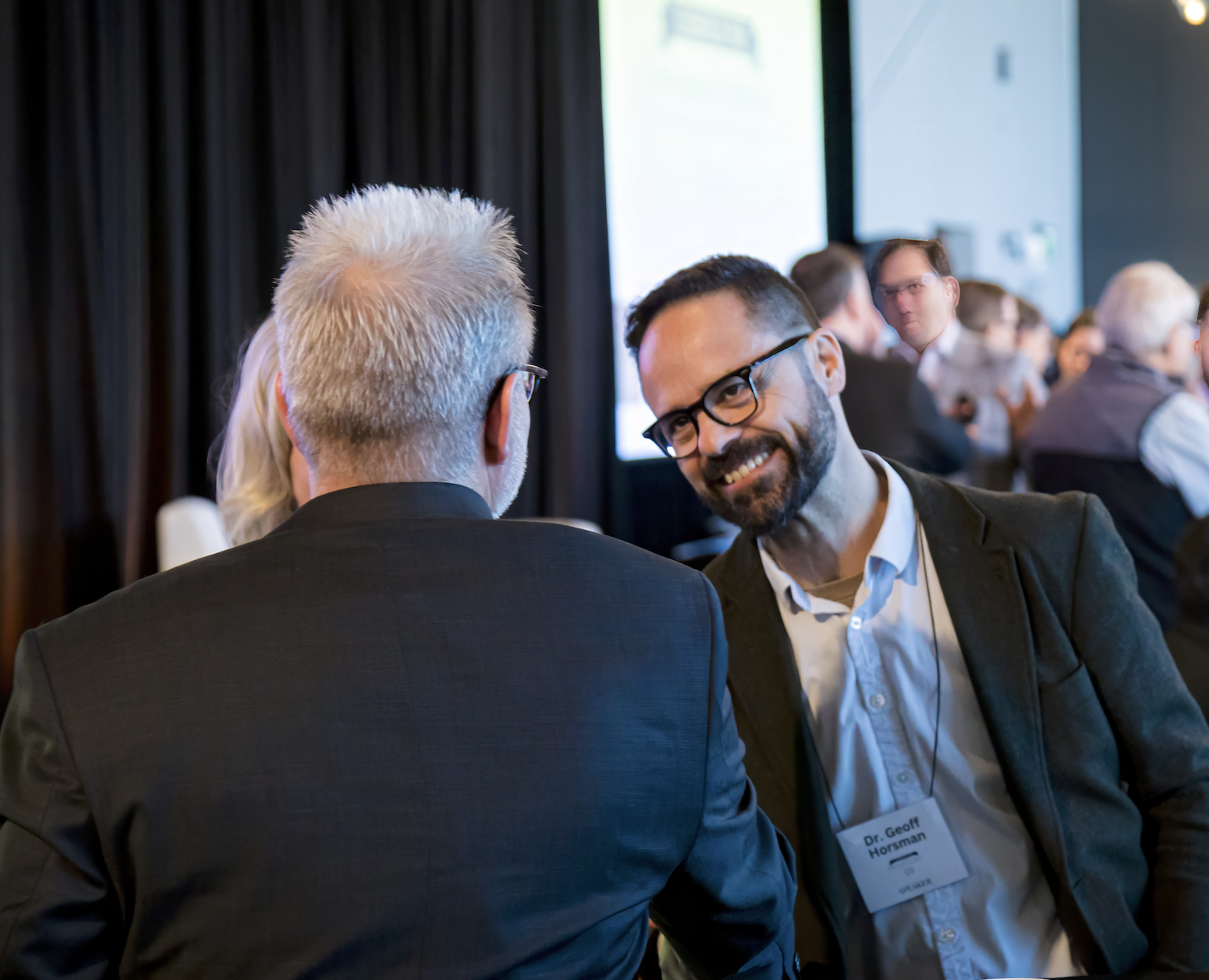 Geoff Horsman speaking with attendees at a conference.